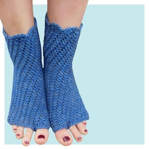 Puede incluir: Un par de calcetines de crochet azul con dedos y un borde festoneado. Los calcetines están hechos con un punto texturizado y se muestran en un par de pies con esmalte de uñas rojo.