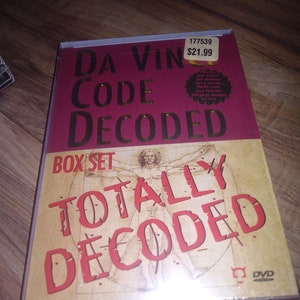 May include: A DVD box set titled "Da Vinci Code Decoded" with a red background and gold lettering. The box set includes a DVD and a book titled "Totally Decoded".