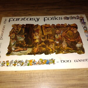 May include: A book cover with the title "Fantasy Folks, paintings the" and the author "Don Weed". The cover features a colorful illustration of a group of fantasy characters, including elves, dwarves, and other mythical creatures.