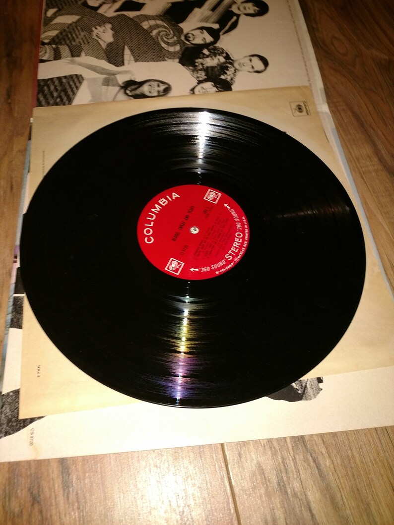 May include: A black vinyl record with a red Columbia Records label. The label has the text "Columbia" and "Stereo" printed on it. The record is on a white surface.