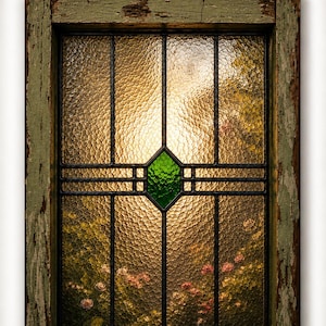 May include: A rectangular window frame with distressed sage green paint containing textured amber glass panels. A central diamond-shaped green glass accent is framed by black metal cames. The text VINTIQUE'S CUSTOM ART PRINTS appears above.
