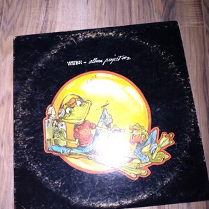May include: A black vinyl record album cover with a yellow, orange, and red illustration of two frogs playing music. The album is titled "WEBN - album project #2".