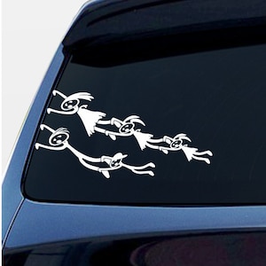 May include: A white vinyl decal of a family of stick figures holding hands and flying through the air. The decal is applied to the rear window of a dark blue car.