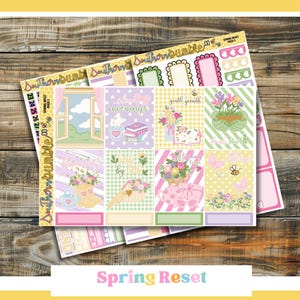 May include: A set of colorful planner stickers with a spring theme. The stickers feature pastel colors, floral designs, and the text "Spring Reset". The stickers are arranged on a wooden surface.