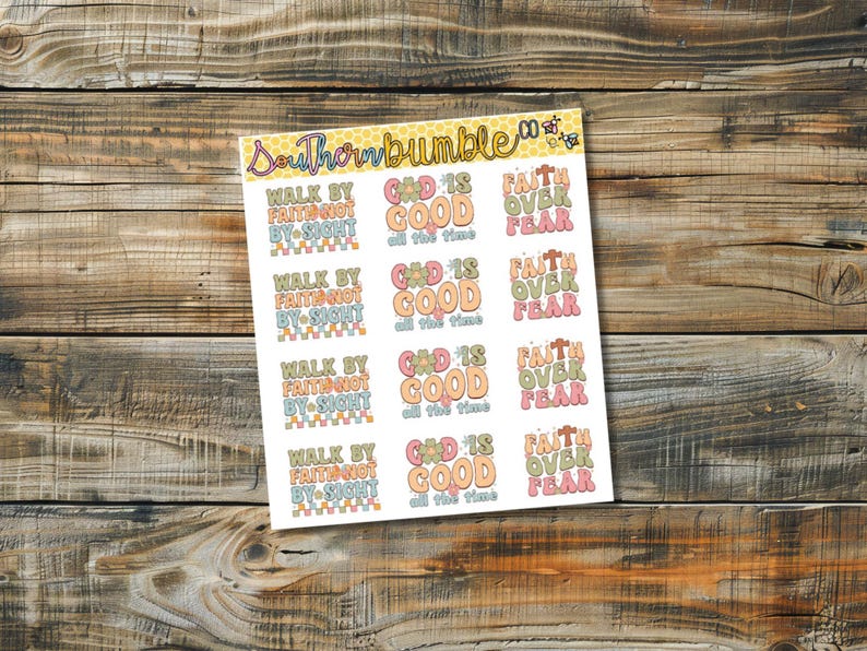 Puede incluir: Una hoja de pegatinas con frases inspiradoras en colores pastel. Las frases incluyen "Camina por fe, no por vista", "Dios es bueno todo el tiempo" y "Fe sobre el miedo". Las pegatinas est&aacute;n sobre un fondo de madera.