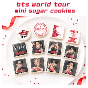 May include: A plate of mini sugar cookies, each individually wrapped. The cookies feature images of a musical group and text that reads "BTS WORLD TOUR" and "ARIRANG". The cookies are decorated with red and black accents.