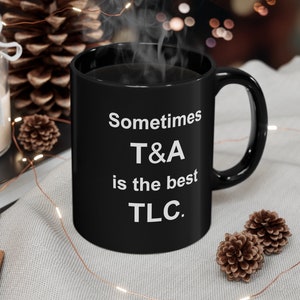 May include: Black coffee mug with white text that reads "Sometimes T&A is the best TLC."
