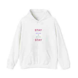 Op de afbeelding: Witte hoodie met de tekst "STAY under the radar & above the fray STAY" gedrukt op de voorkant.