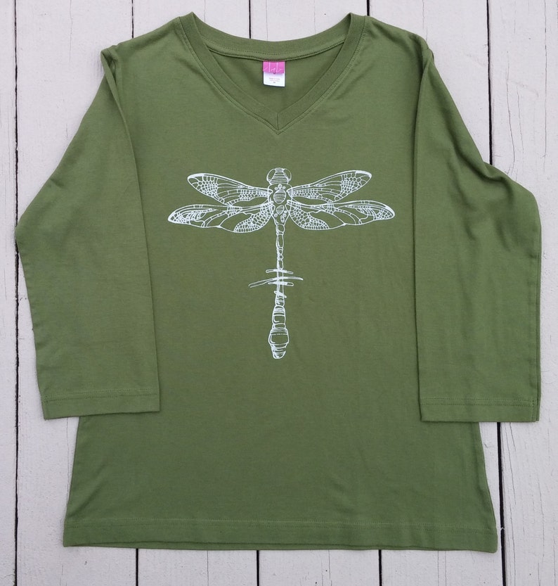 May include: A green long-sleeved shirt with a white dragonfly graphic on the front.