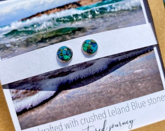 Op de afbeelding: Een paar zilveren oorbel studs met blauwe en groene geplette Leland Blue stenen. De oorbellen zijn handgemaakt en hebben de tekst "my captured journey".