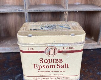 May include: Vintage Squibb Epsom Salt tin. The off-white tin has a red band and text that reads "SQUIBB Epsom Salt." The tin is marked "4 oz." and "E.R. SQUIBB & SONS, NEW YORK."