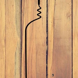 May include: A black silhouette of a corkscrew on a wood background.