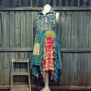 Puede incluir: Un vestido de chaleco vaquero con tejido de patchwork en azul, verde, rojo y blanco. El vestido est&aacute; en un maniqu&iacute; contra un fondo de paneles de madera.
