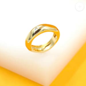May include: A gold ring with a single small diamond set in the center of the band.
