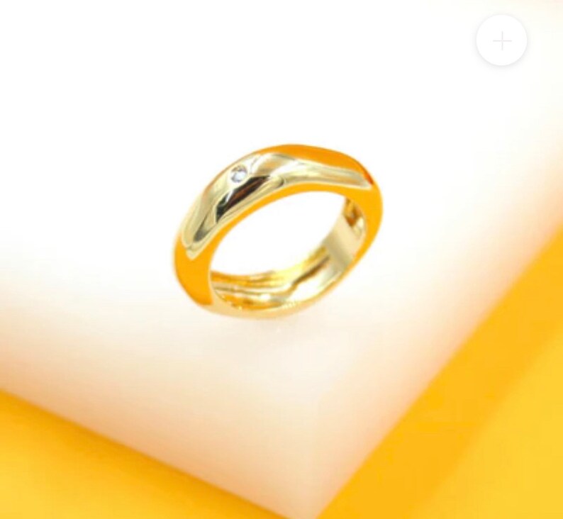 May include: A gold ring with a single small diamond set in the center of the band.