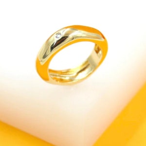 May include: A gold ring with a single small diamond set in the band.