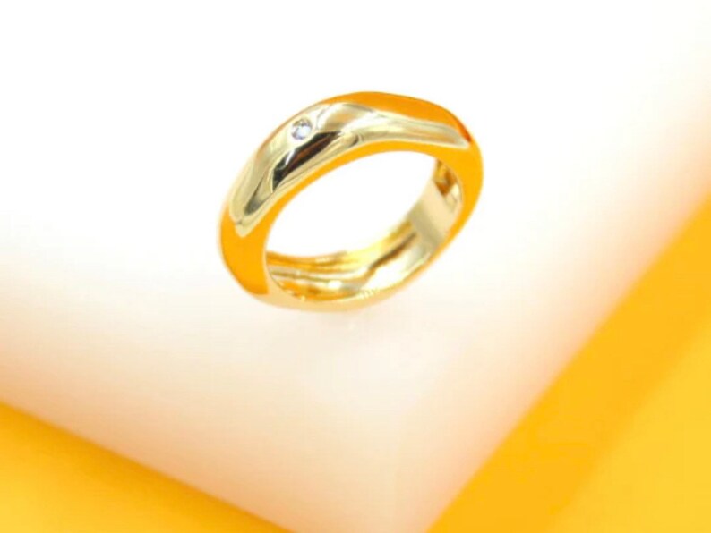May include: A gold ring with a single small diamond set in the band.