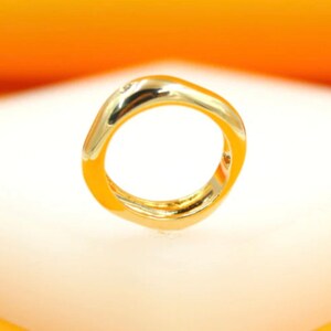 May include: A gold ring with a unique, abstract, and slightly squared shape.