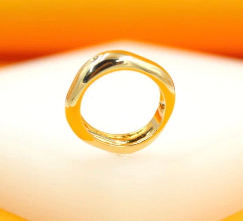 May include: A gold ring with a unique, abstract, and slightly squared shape.