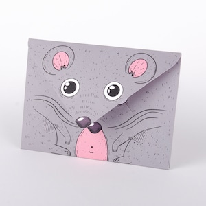 Könnte beinhalten: Ein grauer Umschlag mit einer Cartoon-Maus-Illustration. Die Maus hat große Augen, rosa Ohren und eine rosa Nase. Der Umschlag ist in der Mitte gefaltet und hat einen weißen Hintergrund.
