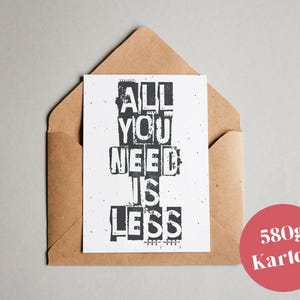 Könnte beinhalten: Eine weiße Karte mit schwarzem Text, der "All You Need Is Less" lautet. Die Karte befindet sich in einem braunen Umschlag. Ein roter Kreis mit weißem Text, der "580g Karton" lautet, befindet sich in der unteren rechten Ecke des Bildes.