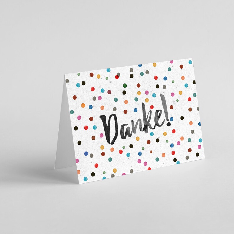 May include: A white card with a colorful confetti pattern and the word "Danke!" written in black.