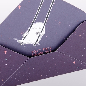 Könnte beinhalten: Ein lila Umschlag mit einem weißen Geist auf einer Schaukel. Der Geist hält eine Blume. Der Umschlag hat ein Sternenmuster und den Text "Keine Panik, noch nicht".