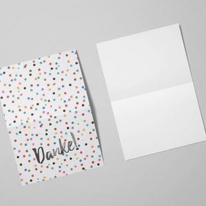 May include: A folded card with a white background and a colorful polka dot pattern. The card says "Danke!" in black script.