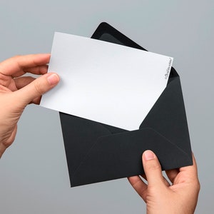 Puede incluir: Una tarjeta blanca con un sobre negro. La tarjeta se est&aacute; sacando del sobre.