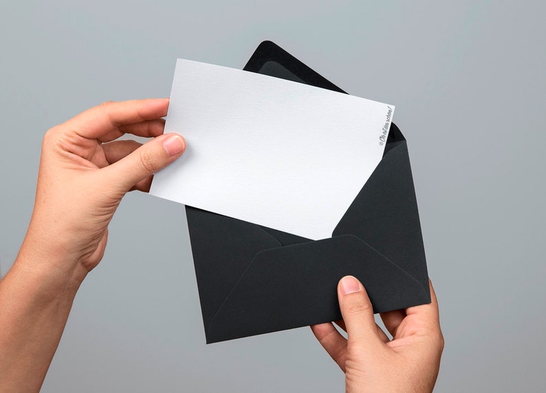 Puede incluir: Una tarjeta blanca con un sobre negro. La tarjeta se est&aacute; sacando del sobre.