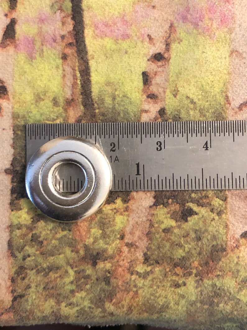 May include: A silver metal washer with a hole in the center. The washer is about 1 inch in diameter.