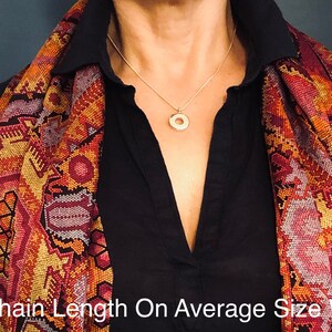 May include: A person wearing a black shirt with a colorful patterned scarf. The person is wearing a silver chain necklace with a round pendant. The text "18" Chain Length On Average Size Woman" is at the bottom of the image.