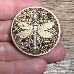 Engraved brass coin featuring a tree of life and dragonfly—symbolizing strength, growth, and transformation.