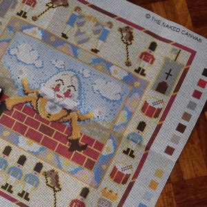 May include: A needlepoint canvas with a colorful design featuring a cartoon character climbing a chimney, a group of toy soldiers, and a drum. The canvas is labeled "The Naked Canvas".