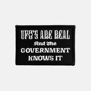 May include: Black embroidered patch with white text that reads "UFO's are real and the government knows it."