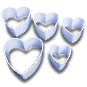 May include: Set of five white plastic heart-shaped cookie cutters of varying sizes.