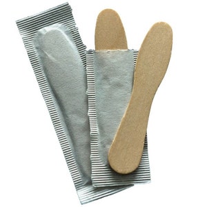 May include: Two wooden ice cream spoons in individual silver foil wrappers. The spoons are light brown and have a rounded shape.