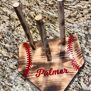 May include: Wooden baseball bat holder shaped like a home plate with red stitching and the name "Palmer" in red lettering.