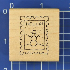 May include: Wooden rubber stamp with a snowman and the word "HELLO!" inside a postage stamp frame.