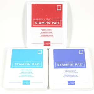 Könnte beinhalten: Drei Stampin' Pad Stempelkissen in Rot, Blau und Türkis. Jedes Stempelkissen ist mit den Worten "Classic Stampin' Pad" und dem Farbnamen beschriftet. Das rote Kissen ist "Sweet Sorbet". Das blaue Kissen ist "Orchid Oasis". Das türkisfarbene Kissen ist "Tahitian Tide".