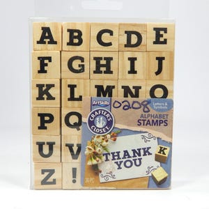 以下が含まれることがあります： 透明なプラスチック製の箱に入った、30個の木製アルファベットスタンプのセット。スタンプはアルファベット順に並べられており、大文字と感嘆符が含まれています。箱には、「ありがとう」と書かれた小さなカードと、小さな木製の「K」のスタンプも含まれています。