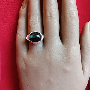 May include: A silver ring with a black and green oval gemstone.