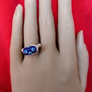 May include: A ring with a blue and white glass bead wrapped in silver wire.