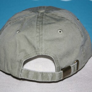 May include: A plain, light green baseball cap with a fabric strap and a buckle closure. The cap is made of a soft, cotton material.