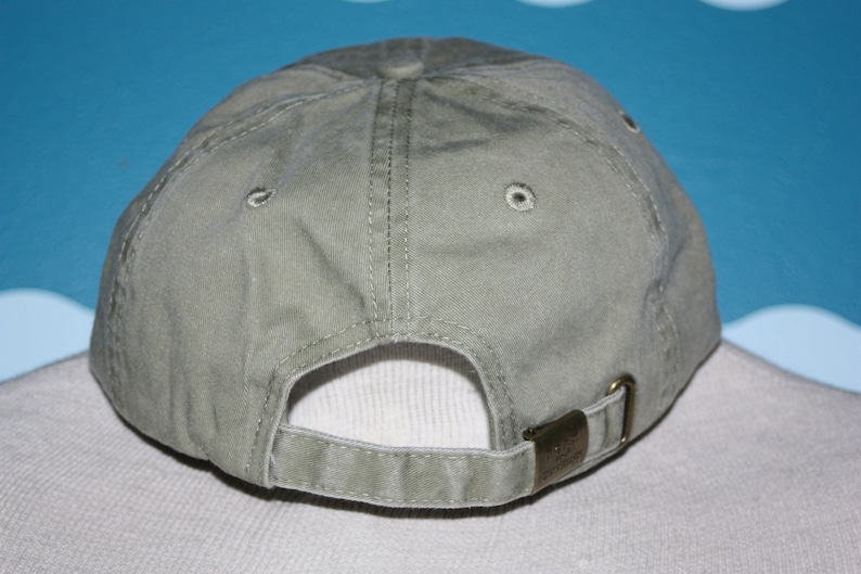 May include: A plain, light green baseball cap with a fabric strap and a buckle closure. The cap is made of a soft, cotton material.