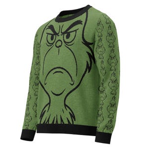 Peut inclure: Pull vert avec un grand contour noir du visage d'un personnage grincheux sur le devant. Les manches présentent un motif répété du même visage de personnage. Le pull a un col et des poignets noirs.