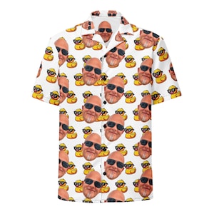 Puede incluir: Una camisa blanca de manga corta con botones que presenta un patrón repetitivo en toda la prenda de una persona calva con gafas de sol negras y patitos de goma amarillos que también llevan gafas de sol negras.