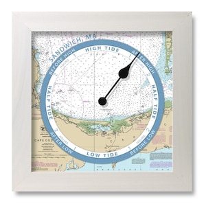 May include: A nautical tide clock with a black hand pointing to the time. The clock face is a map of the Sandwich, MA area with the words "SANDWICH, MA" and "HIGH TIDE" printed on the face.