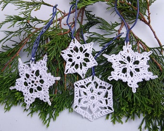 Set of 4 white crochet snowflakes with silvery accents.