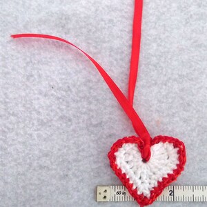 White crochet valentine heart trimmed with red sparkly sequin trim and a satin ribbon. Sweet little holiday gift idea for someone you love. image 3
